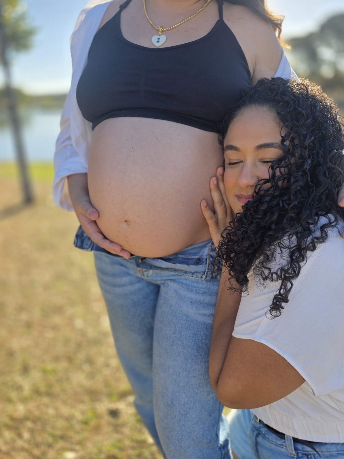Menina encostando o rosto na barriga da gestante durante ensaio externo
