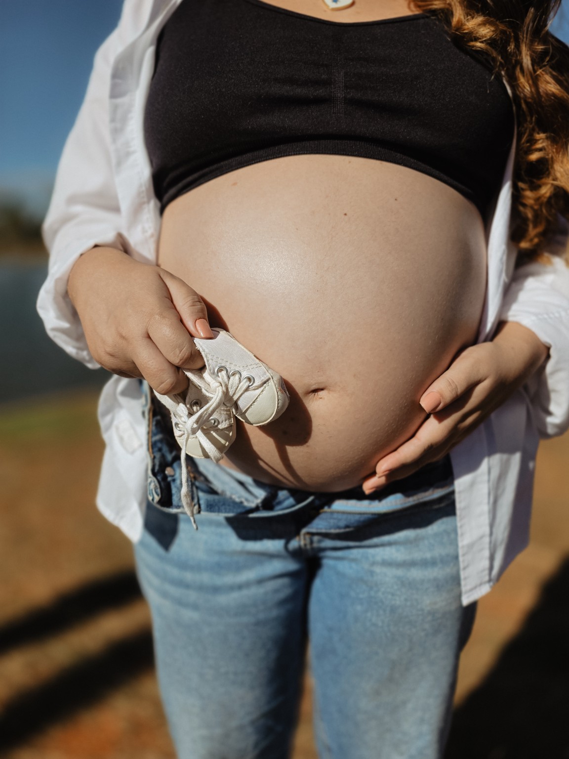 Gestante segurando pequenos sapatinhos sobre a barriga